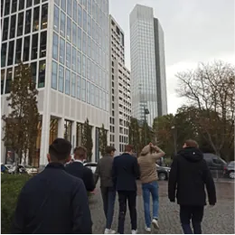 Gruppe von hinten auf dem Weg durch ein Viertel mit Hochhäusern.